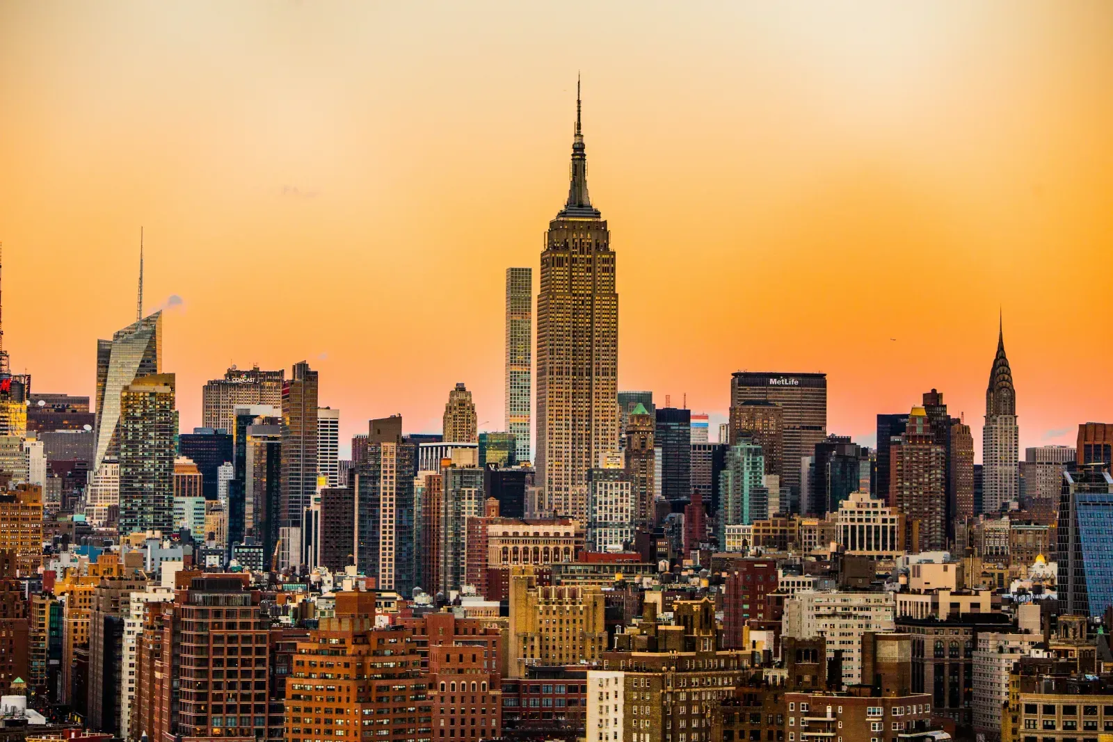Die Skyline von Manhattan mit dem Empire State Building vor einem orangefarbenen Abendhimmel.