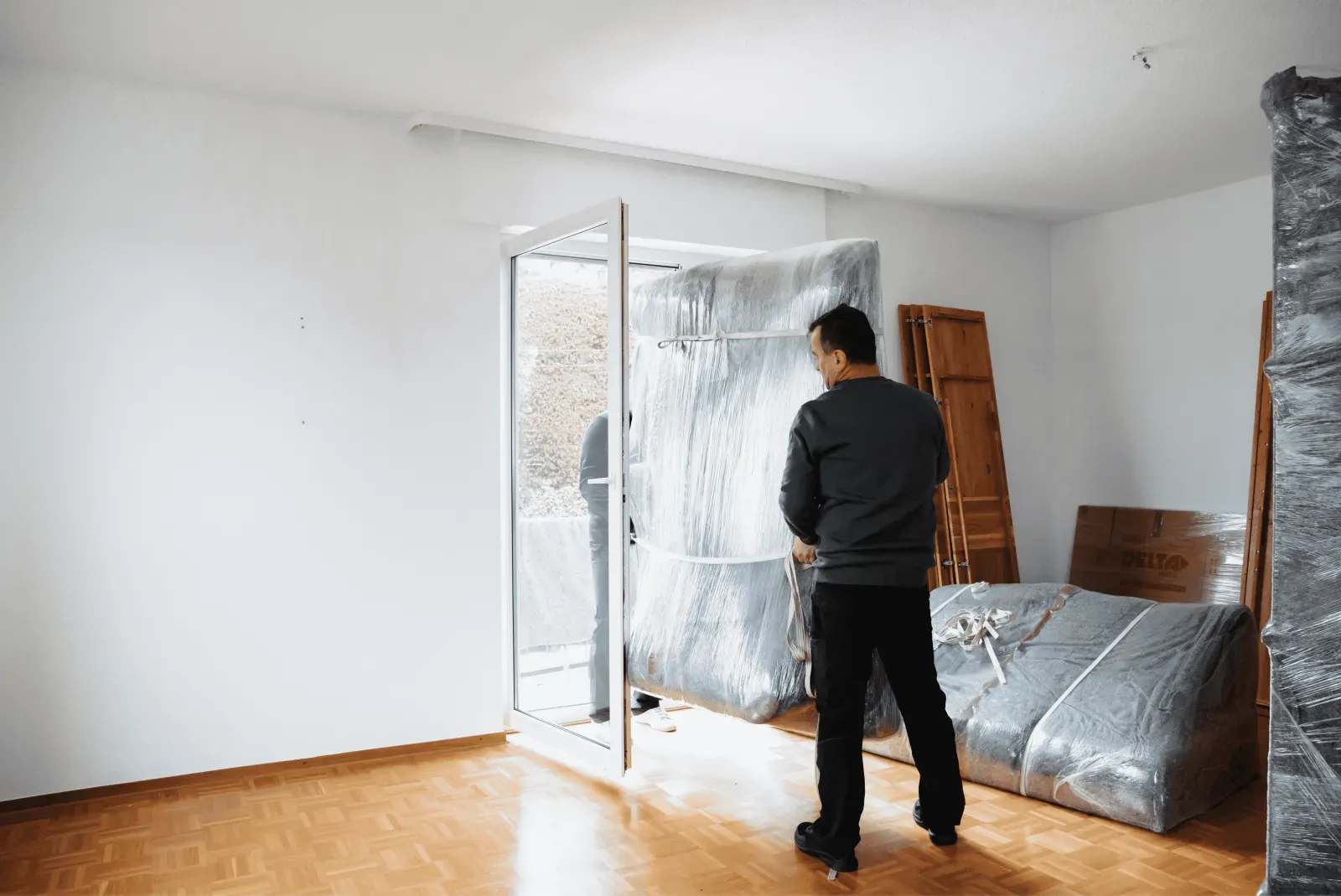 Ein Umzugshelfer bereitet ein Möbelstück am Ausgang vor – Symbolbild