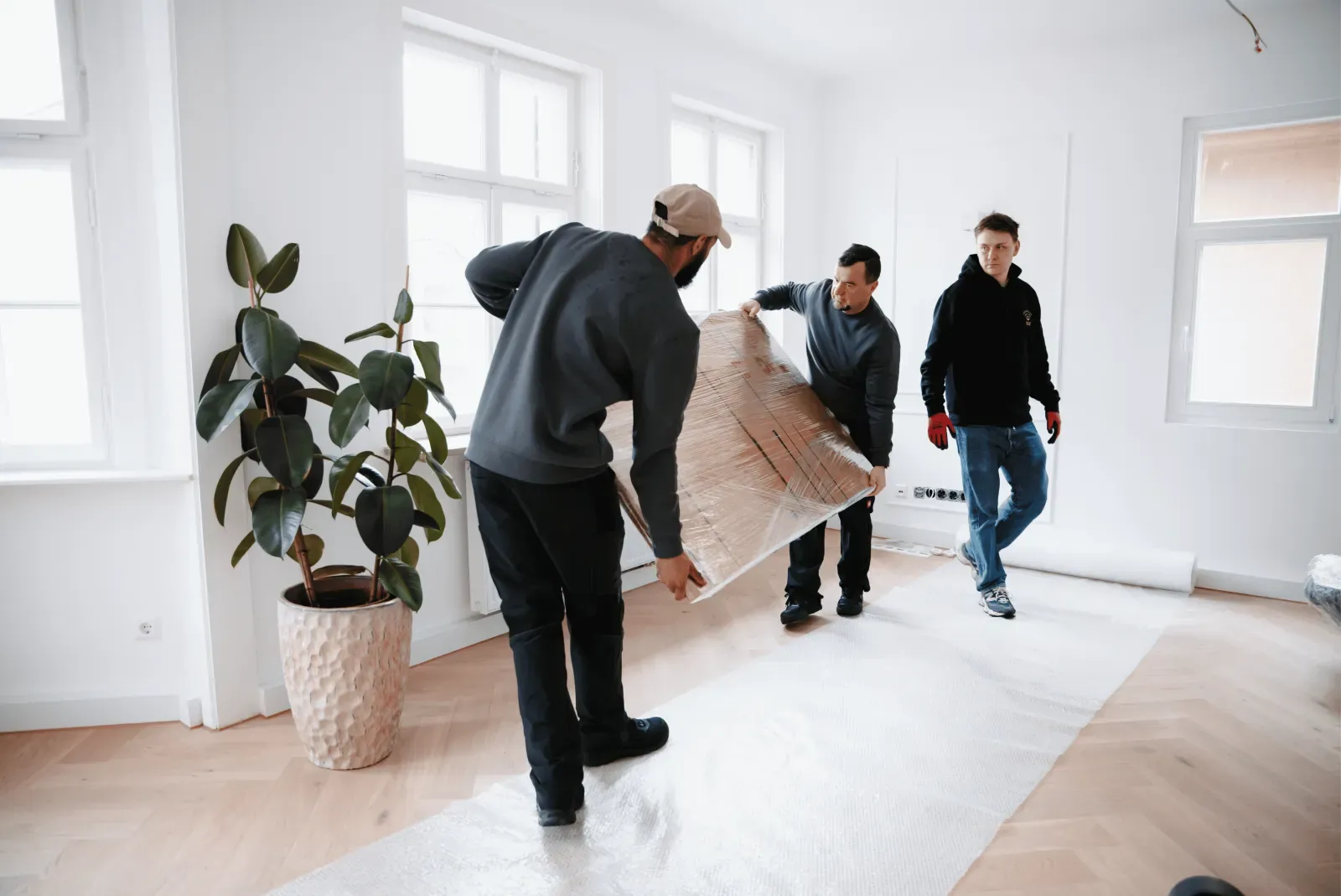 Umzugshelfer tragen ein Möbelstück durch einen Wohnraum – Symbolbild
